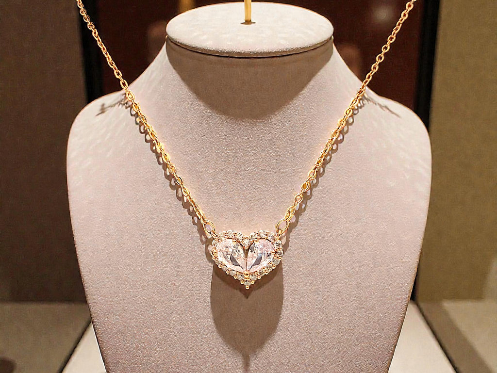 Gold necklace with a heart-shaped pendant on a mannequin bust.