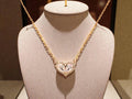 Gold necklace with a heart-shaped pendant on a mannequin bust.